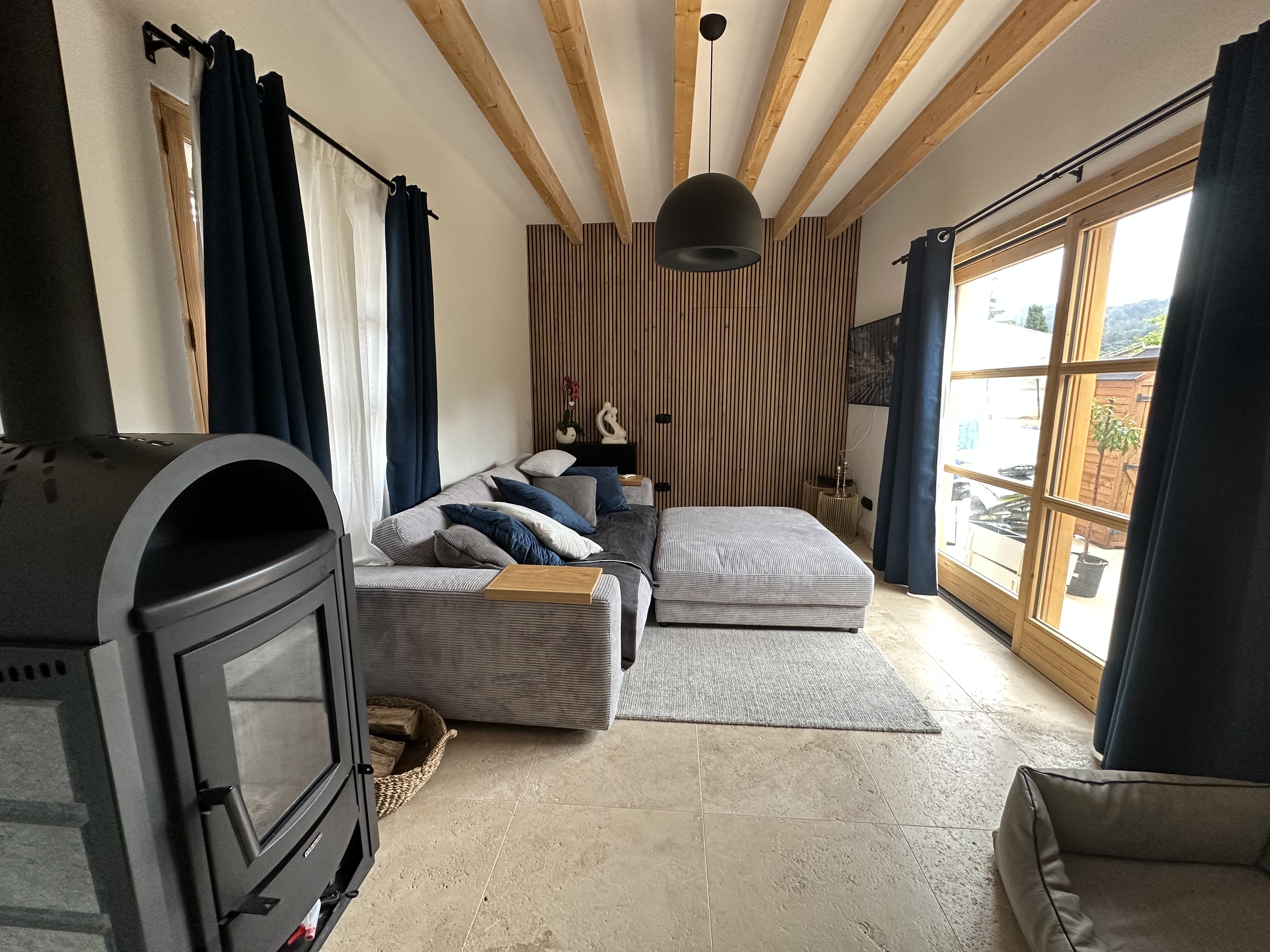 Salón con chimenea de diseño, vigas de madera y grandes ventanales al jardín